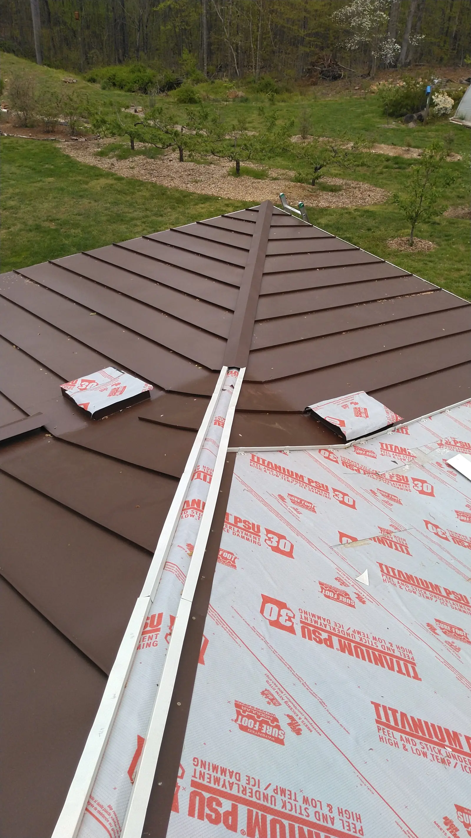 Brown metal panel starter edge over underlayment with a drip edge at the eave.