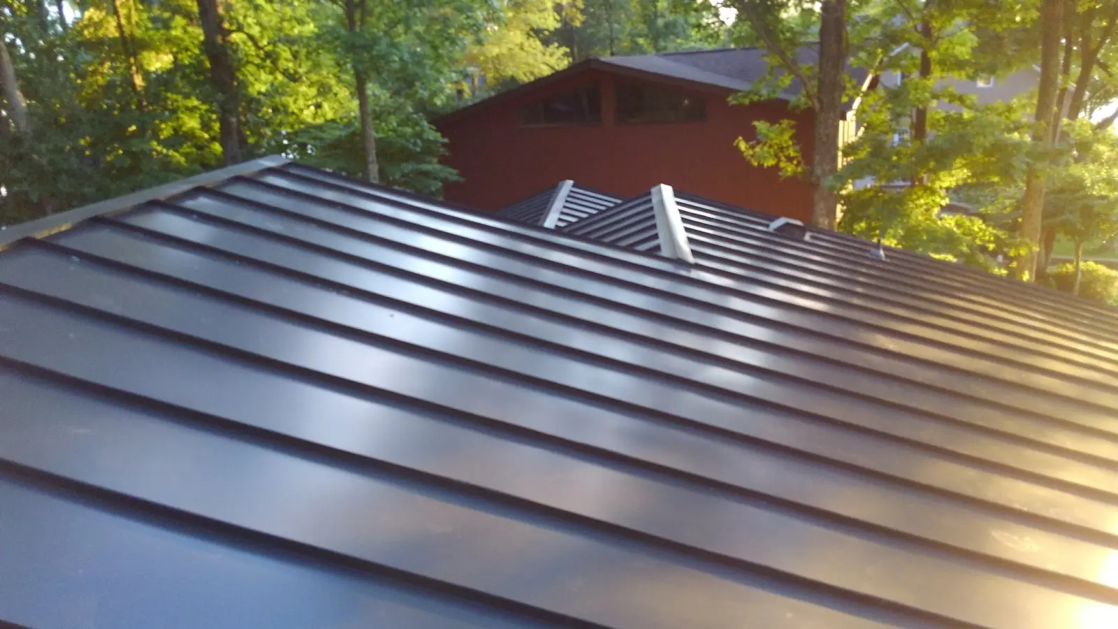 Lake house roof before and after: gray shingles then dark standing seam