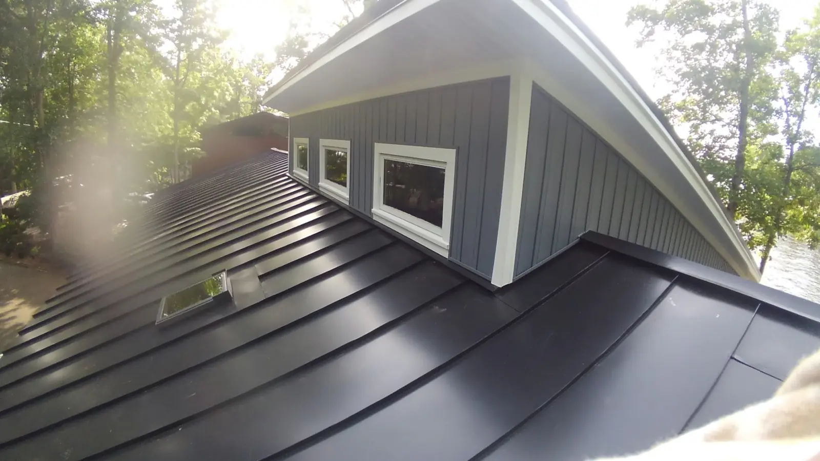 Lake house dormer before and after: gray shingles then dark standing seam