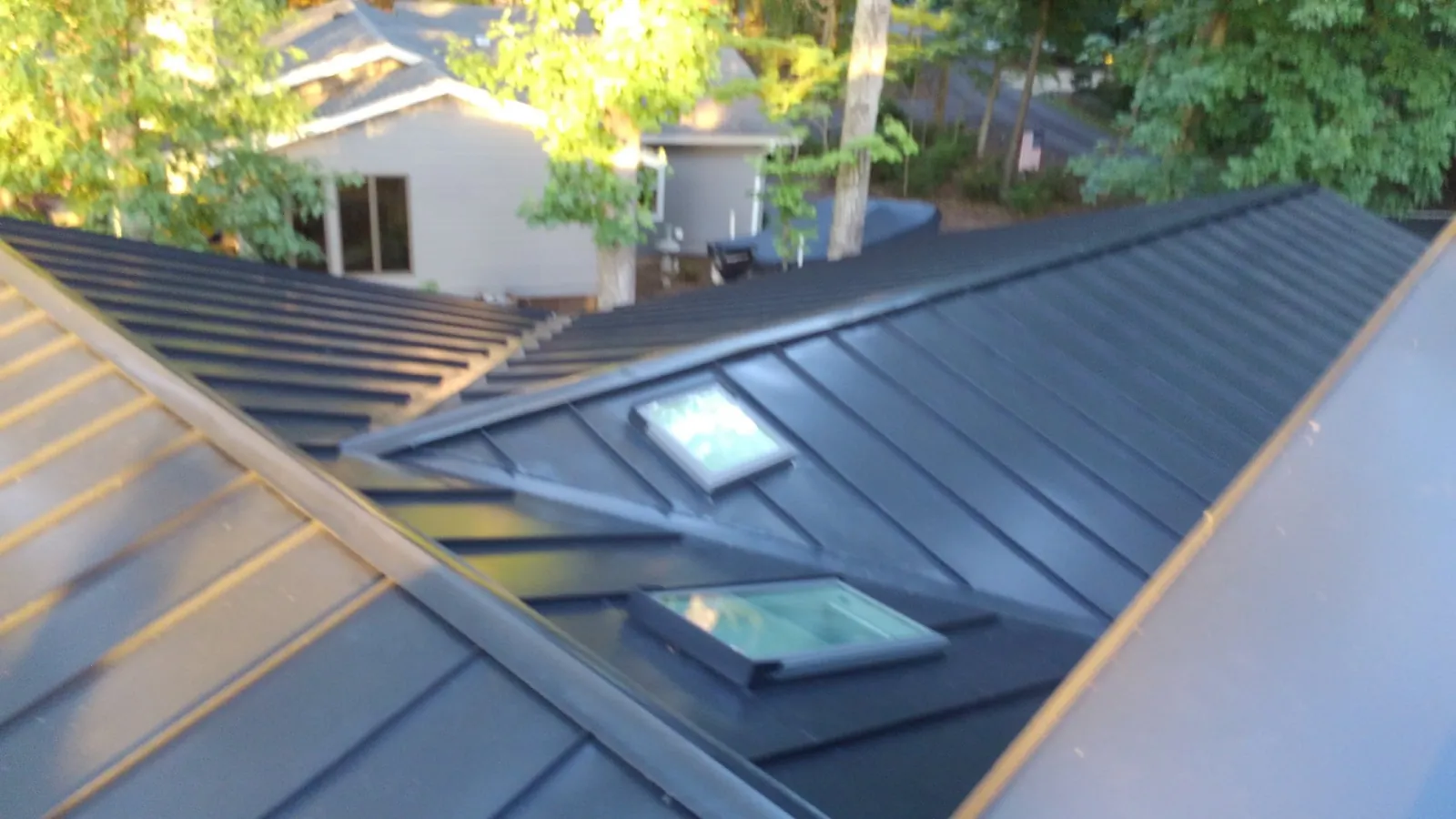 Two skylights set into a dark standing seam metal roof with clean flashing at the seams.