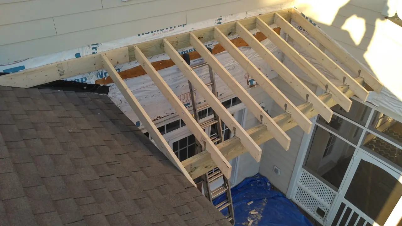 Open roof rafters over a porch opening beside shingles and a blue tarp.