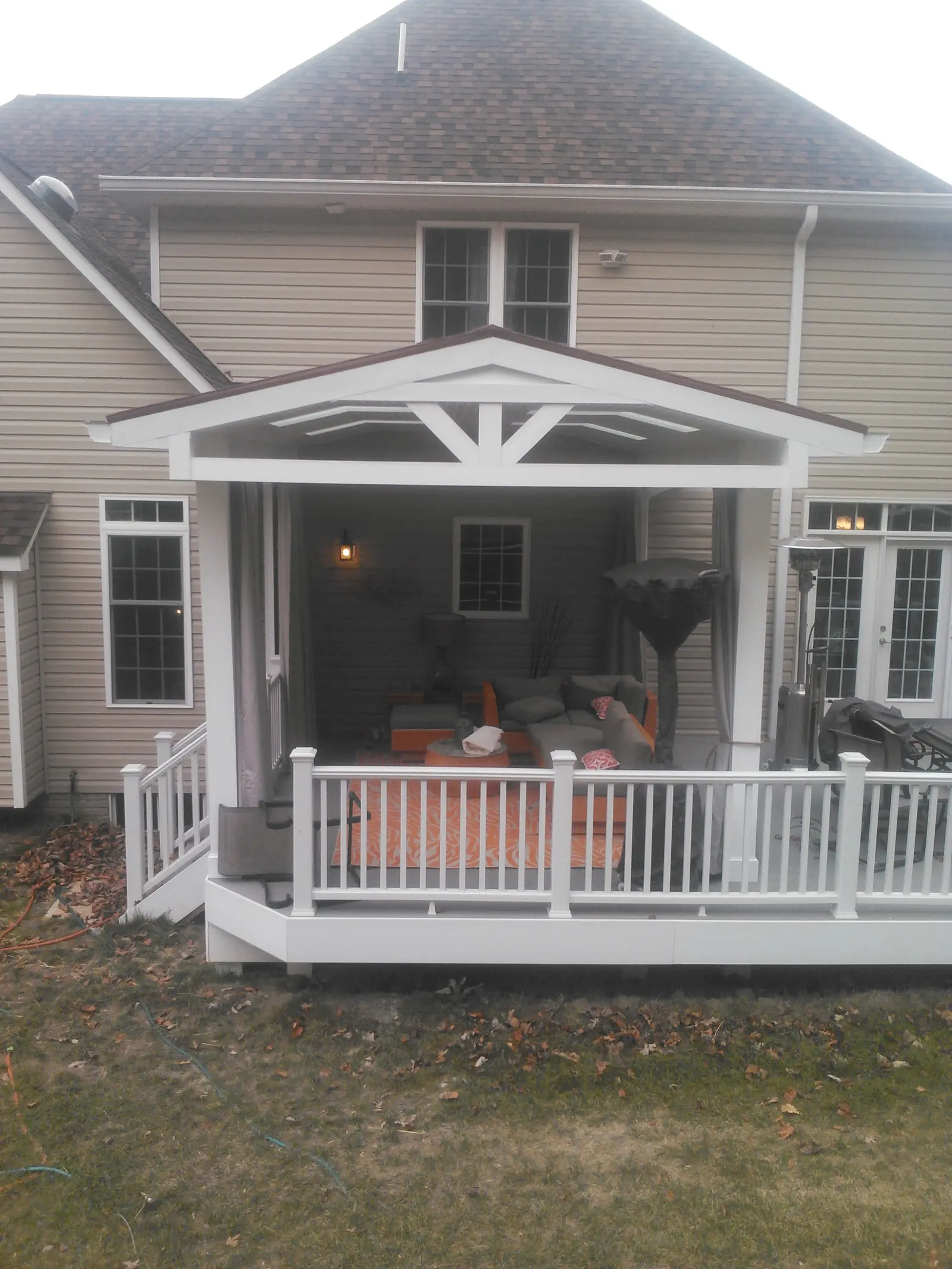 Covered back porch with a white gabled roof frame, skylights and a deck railing.